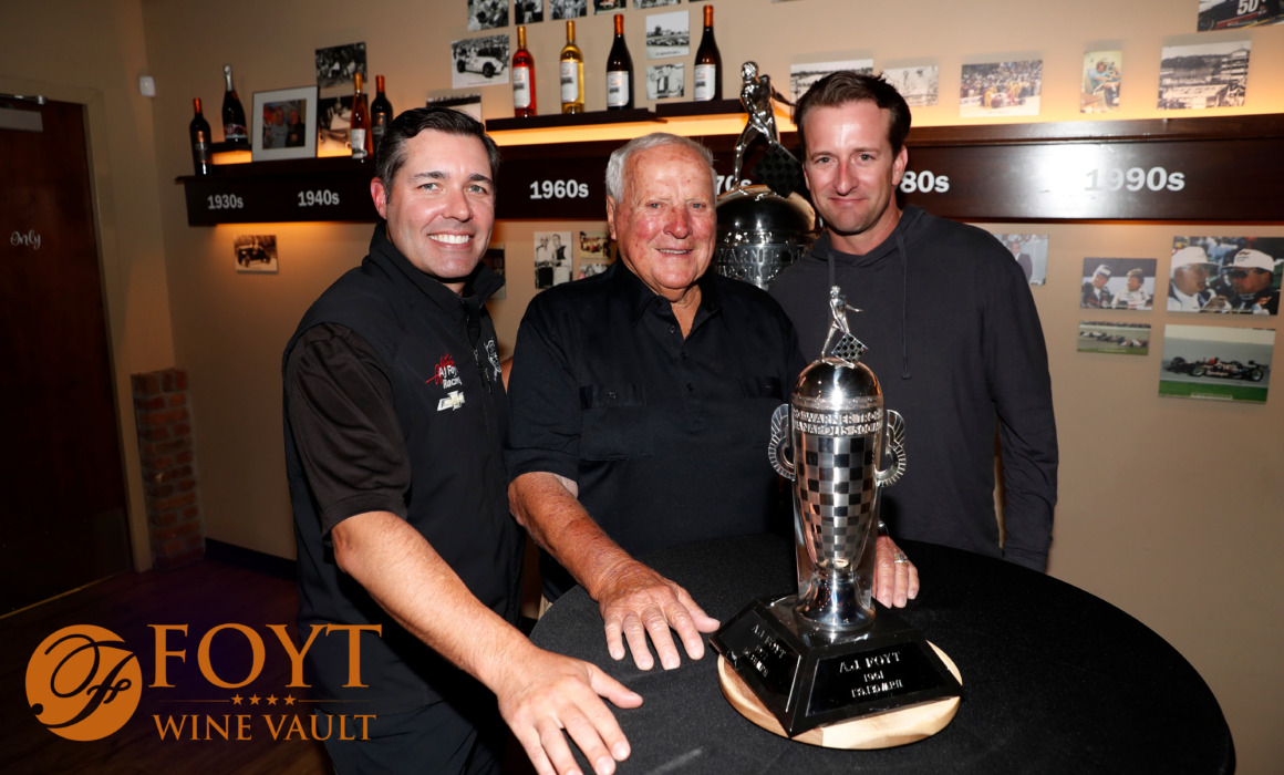 Three men posing behind a trophy
