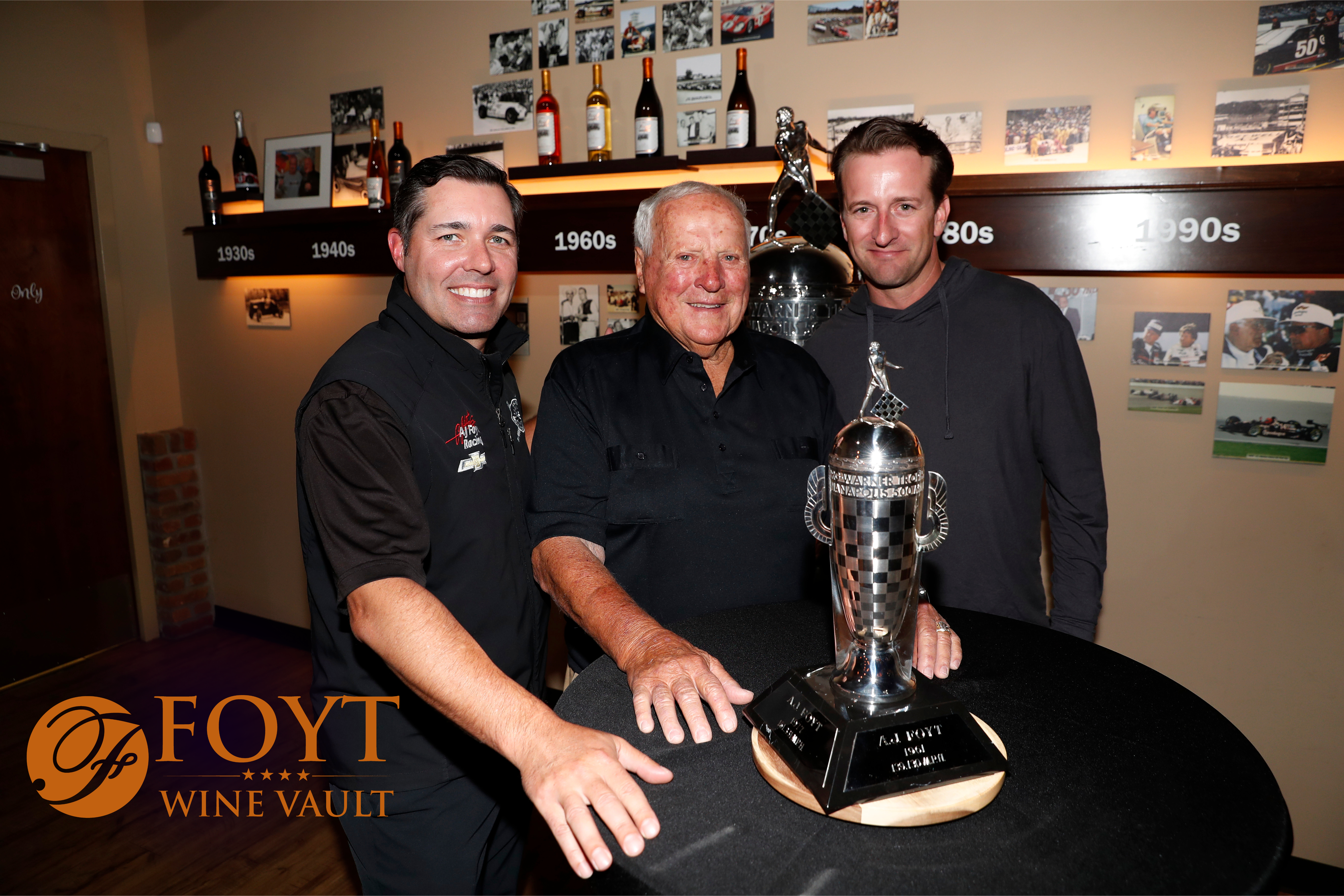 Three men posing behind a trophy